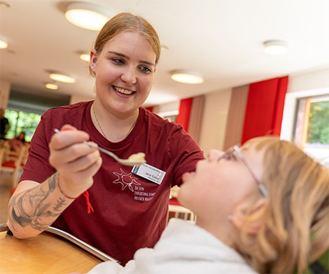 Portr�t Jana hilft Kind beim Essen